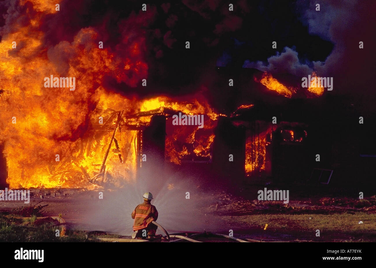 Ein einsamer Feuerwehrmann kämpft ein Feuer in einem brennenden Gebäude Stockfoto