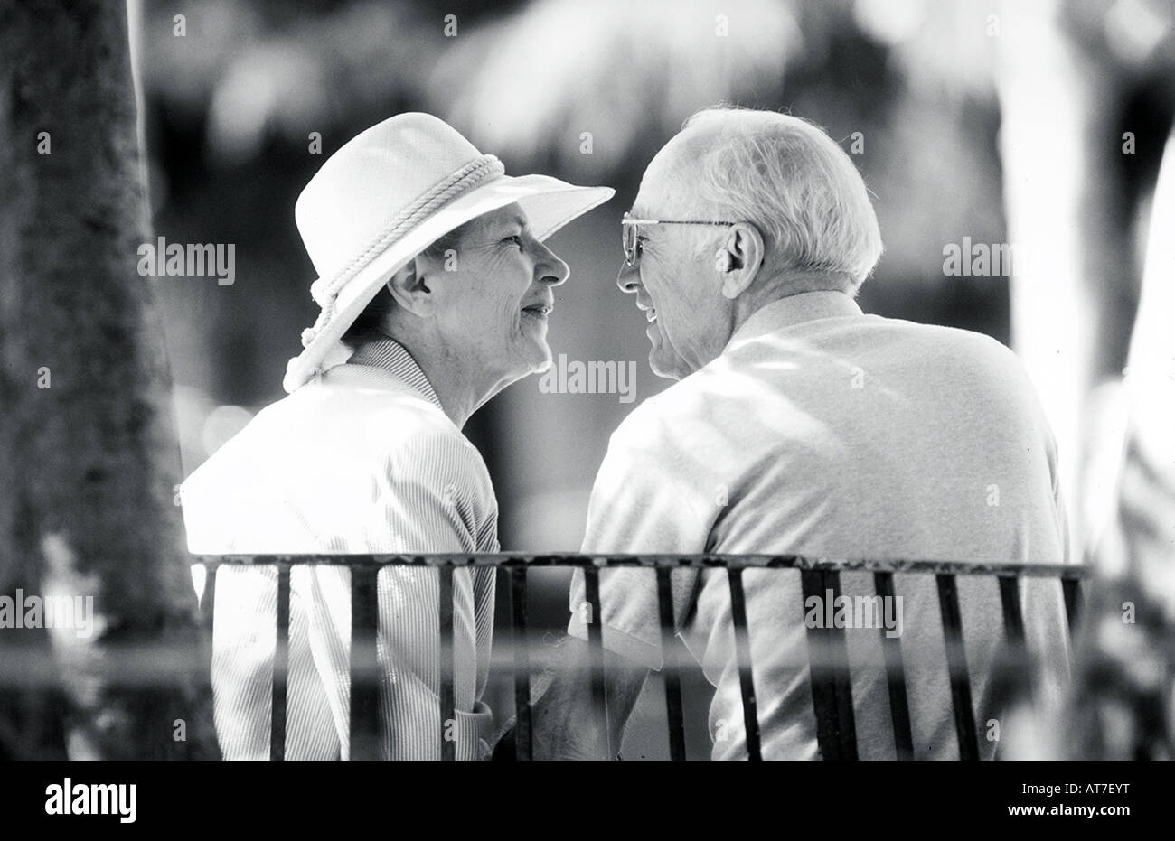 Ein älteres Paar eng auf einer Parkbank im Gespräch Stockfoto