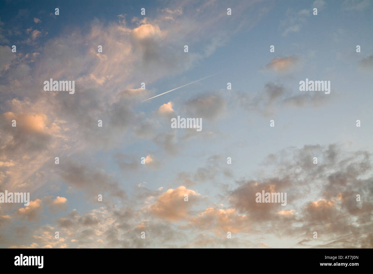 Sonnenuntergang über Findon Dorf, West Sussex. Ein Jet fliegt hoch über eine Dampf-Spur in die Wolken. Stockfoto