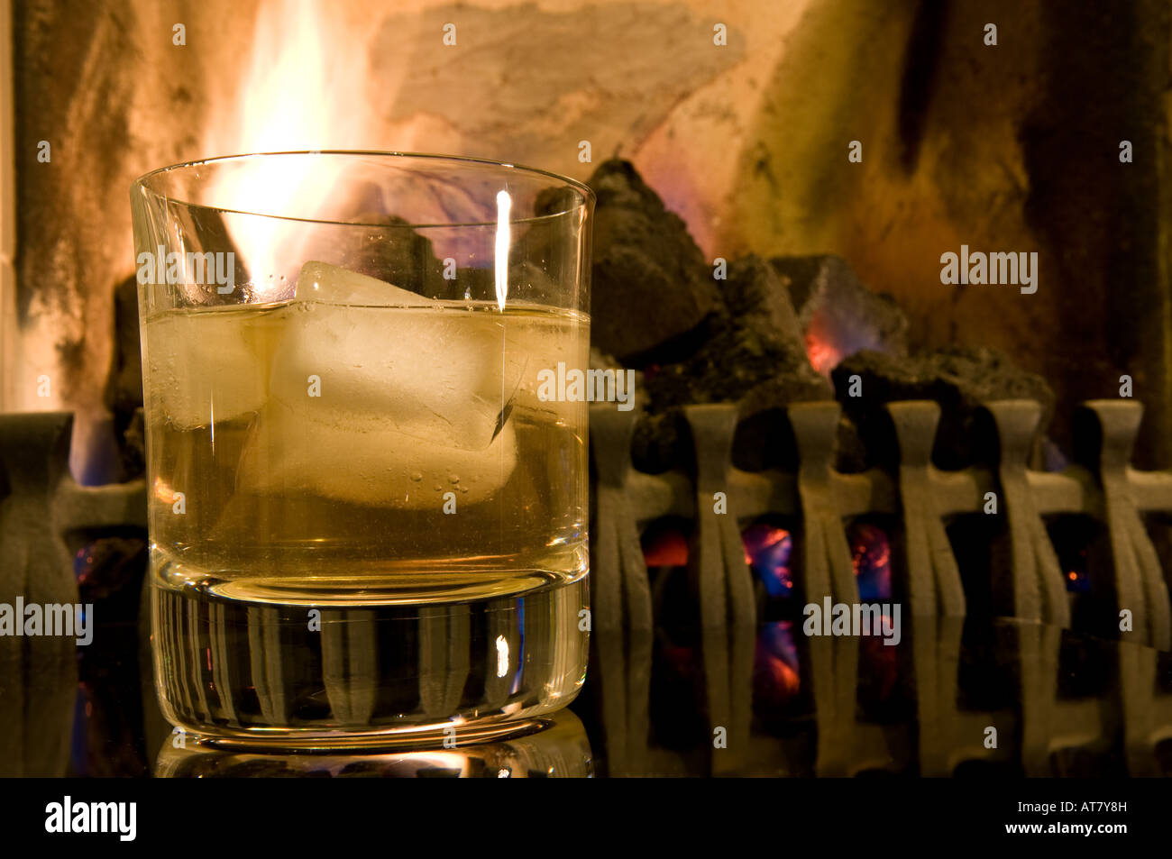 Ein Glas Scotch Whisky auf den Felsen vor einem Kaminfeuer. Stockfoto