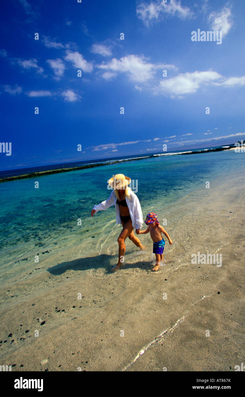 Mutter und Sohn in Hüte zu Fuß am Strand an einem sonnigen Tag in Hawaii Stockfoto