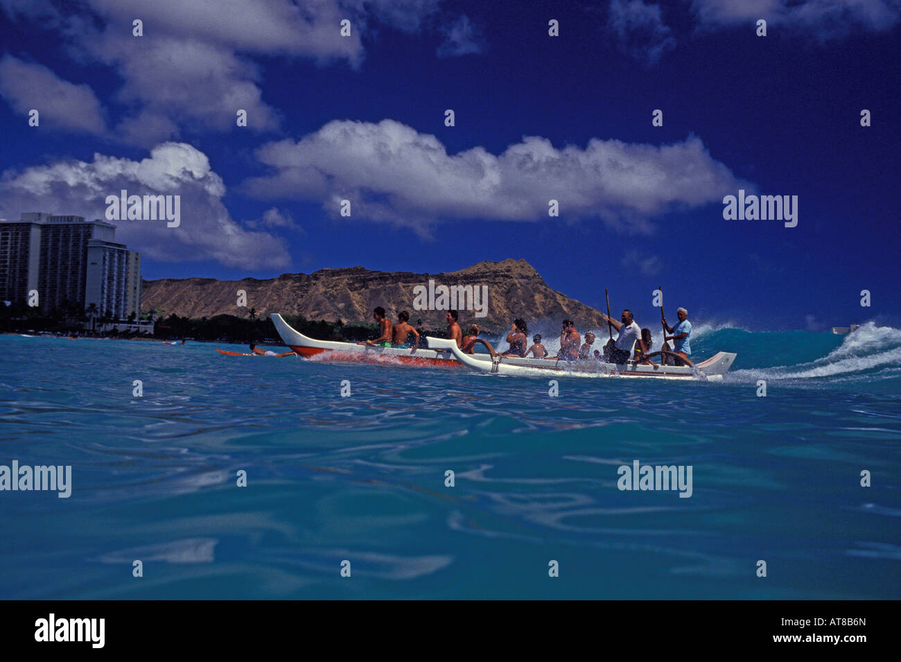 Tolles Foto von zwei Ausleger-Kanus voller Touristen ausrollen auf der perfekten Welle in Richtung der Küste von Waikiki Beach. Stockfoto
