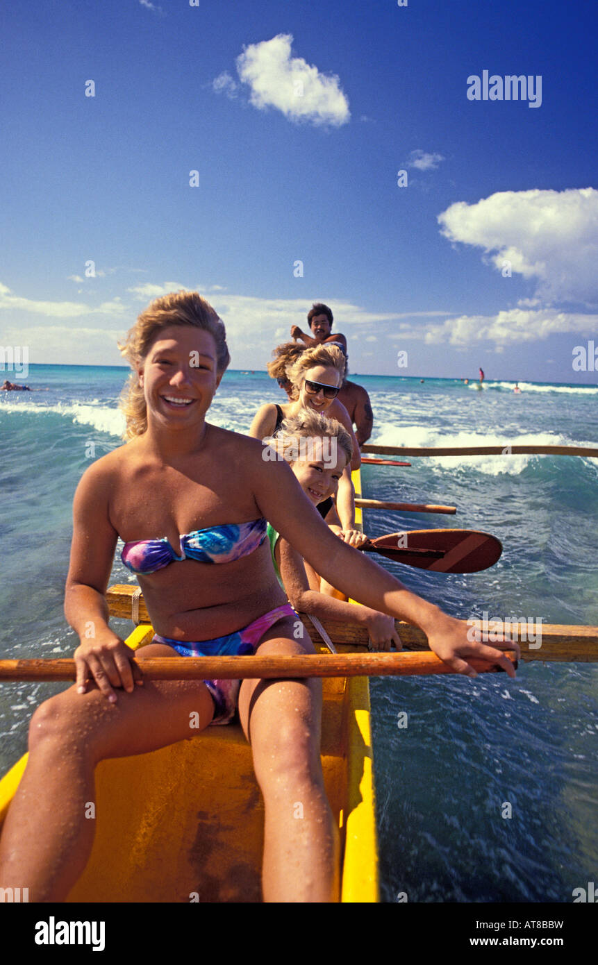 Wasser & Sonne verwöhnten Urlauber Lächeln mit Freude auf gelben Auslegerkanu gleiten auf schönen blauen Gewässern vor Waikiki Beach Stockfoto