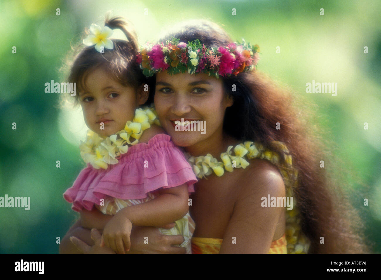 Nahaufnahme einer schönen polynesischen Frau mit ihrer Tochter in bunten aloha tragen und tragen Plumeria und Huku Leis. Satz Stockfoto