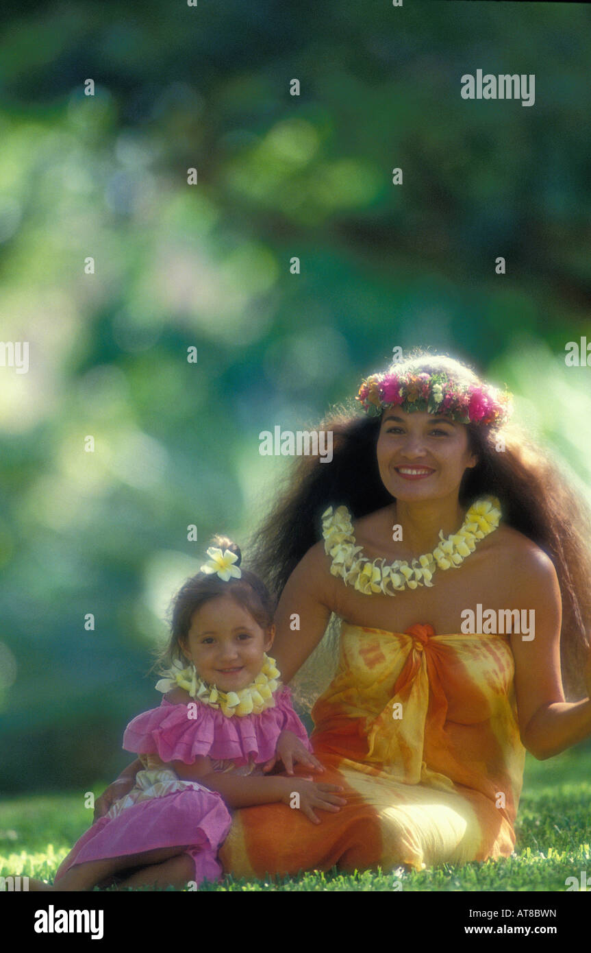 schöne polynesischen Frau mit ihrer Tochter, beide bekleidet mit bunten aloha tragen und tragen Plumeria und Haku Leis, sitzen Stockfoto