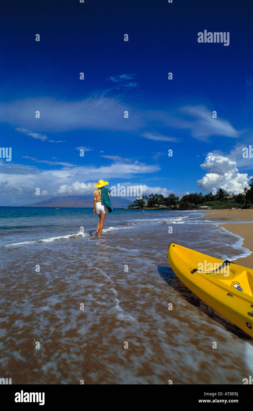 Eine Frau geht Wailea Strand entlang mit dem gelben Kajak im Vordergrund. Stockfoto