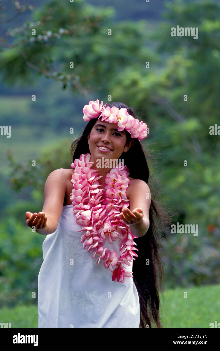 Junge Frau tanzt Hula in der Nähe der Koolau Berge tragen rosa Plumeria leis Stockfoto