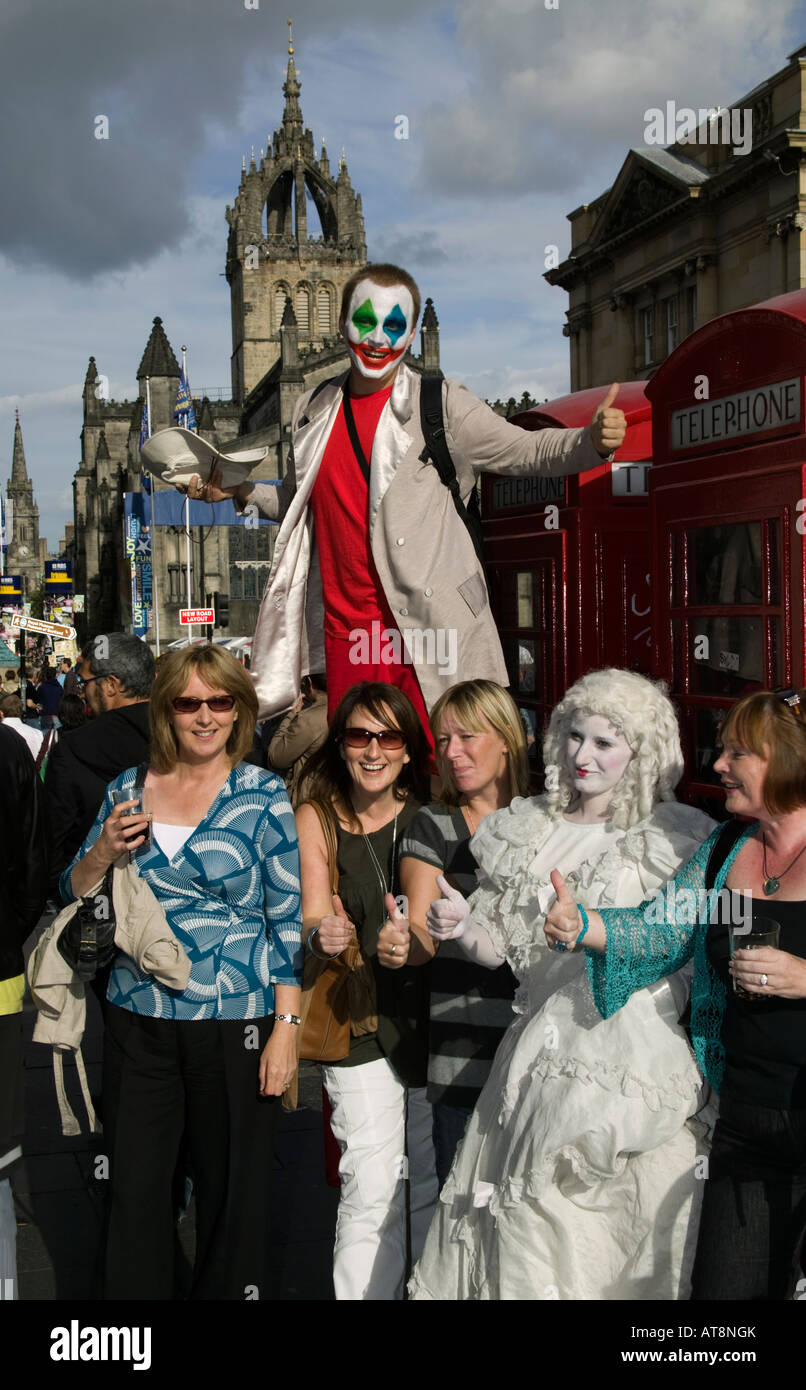 Straßenkünstler auf Stelzen posiert für Fotos mit Frauen in der Royal Mile, Edinburgh Fringe Festival, Schottland, UK, Europa Stockfoto