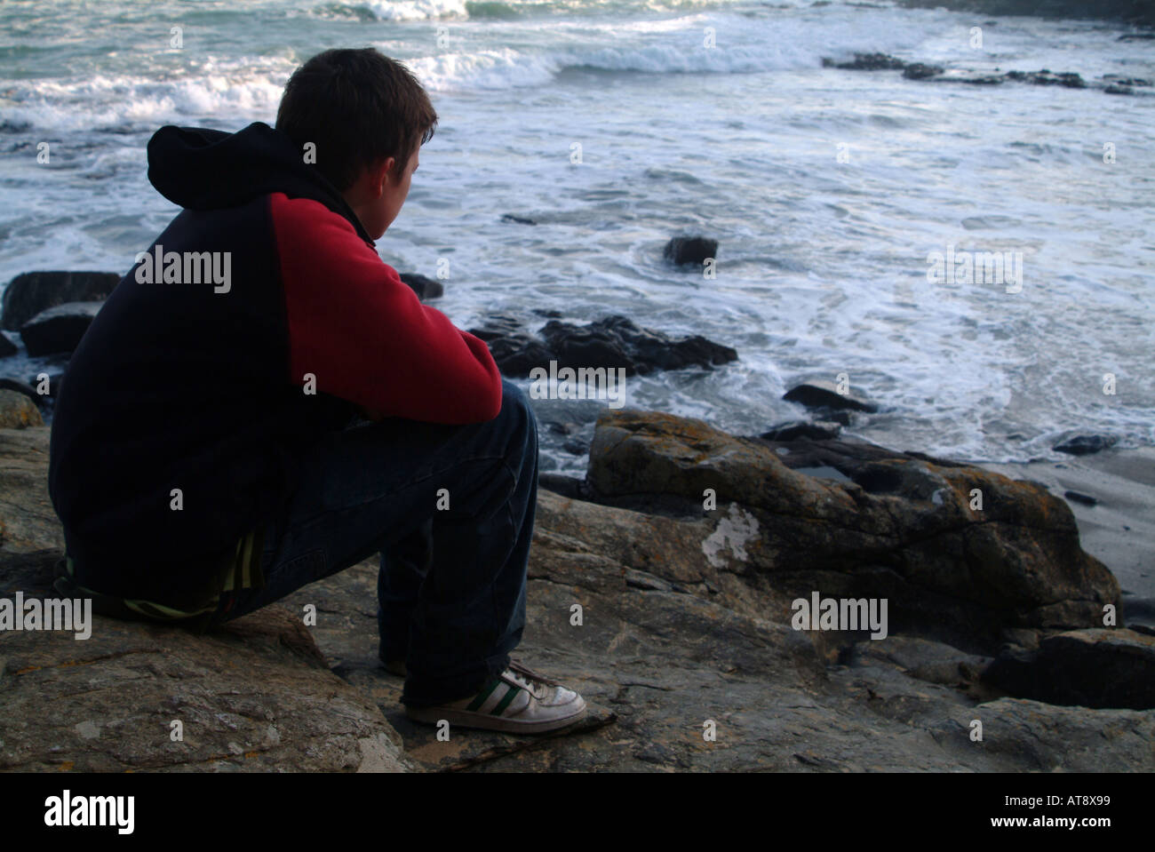 Rückansicht eines Teenagers auf Felsen sitzen und Blick auf die Adria Stockfoto