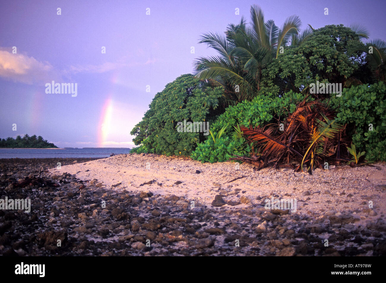 Ein Regenbogen steigt vertikal in den Pazifischen Ozean in der Nähe von das felsige Ufer des isolierten Mili-Atoll in den Marshall-Inseln. Stockfoto