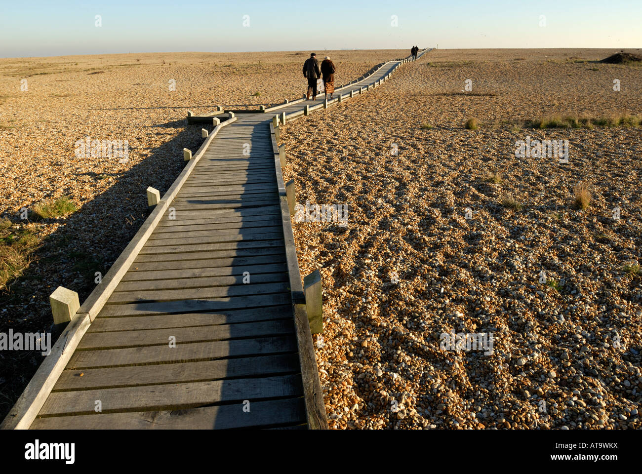 Zwei Paare zu Fuß entlang der Promenade in Richtung Meer bei Dungeness, Kent, UK. Stockfoto