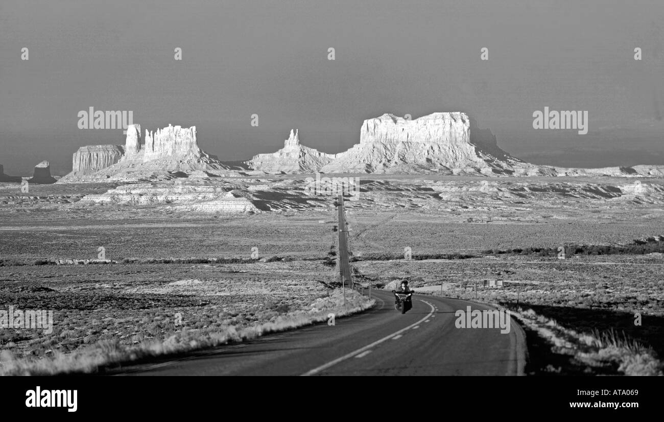 USA Arizona Monument Valley Highway Motocyle bei Sonnenaufgang ganz allein auf der Straße schwarz / weiß Stockfoto