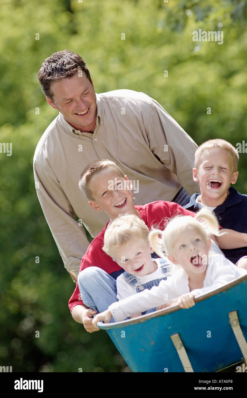 Vater geben Kinder Fahrt in Schubkarre Stockfoto