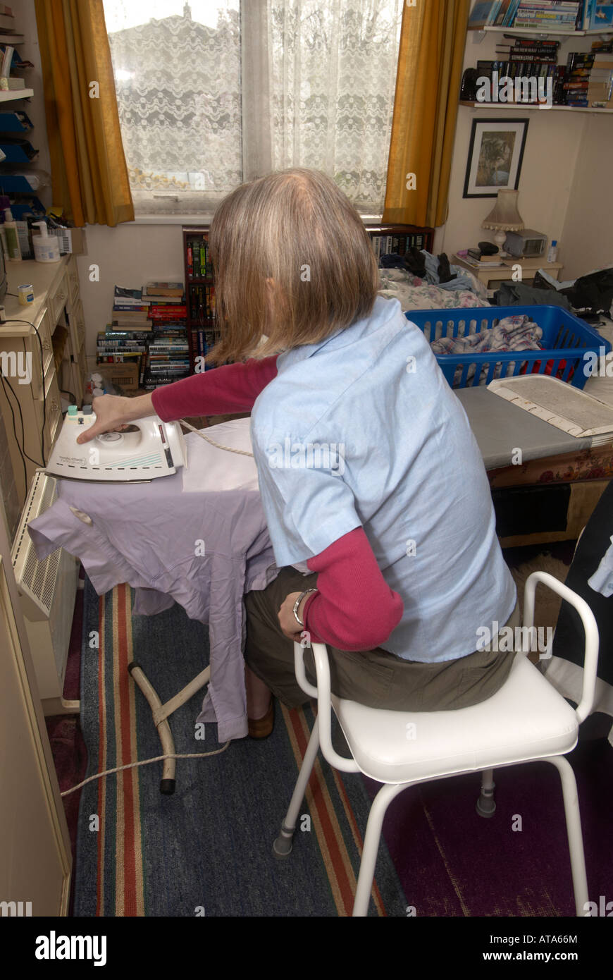 Dame auf ungültige Hocker Bügeln im Schlafzimmer, ihr Haarausdünnung aufgrund von Chemotherapie zu tun Stockfoto