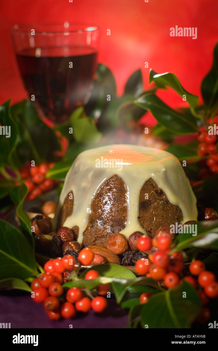 Britische Whisky und Obst Christmas Pudding mit Holly, Obst und Nüssen, Rotwein, brandy Sauce auf Pudding, Dampf steigt Stockfoto