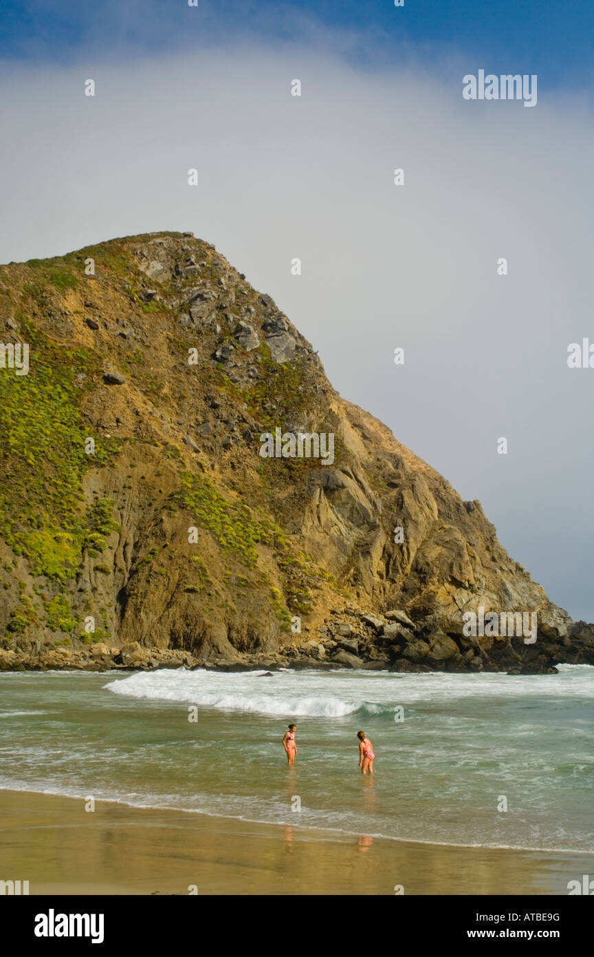 Junge Frauen spielen in den Wellen des Ozeans unter Küste Felsen Pfeiffer Beach Big Sur Küste Monterey County Kalifornien Stockfoto
