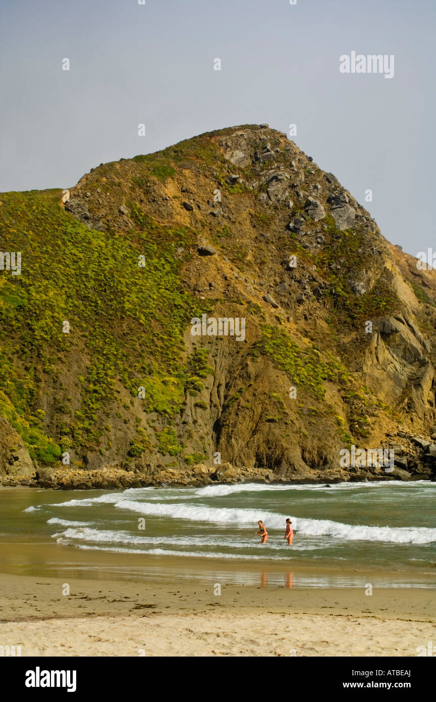 Junge Frauen spielen in den Wellen des Ozeans unter Küste Felsen Pfeiffer Beach Big Sur Küste Monterey County Kalifornien Stockfoto
