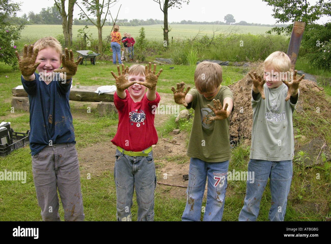 Kinder einer Grundschule hat einen Ofen aus Brickearth zeigen ihre schmutzigen Hände bauen Stockfoto