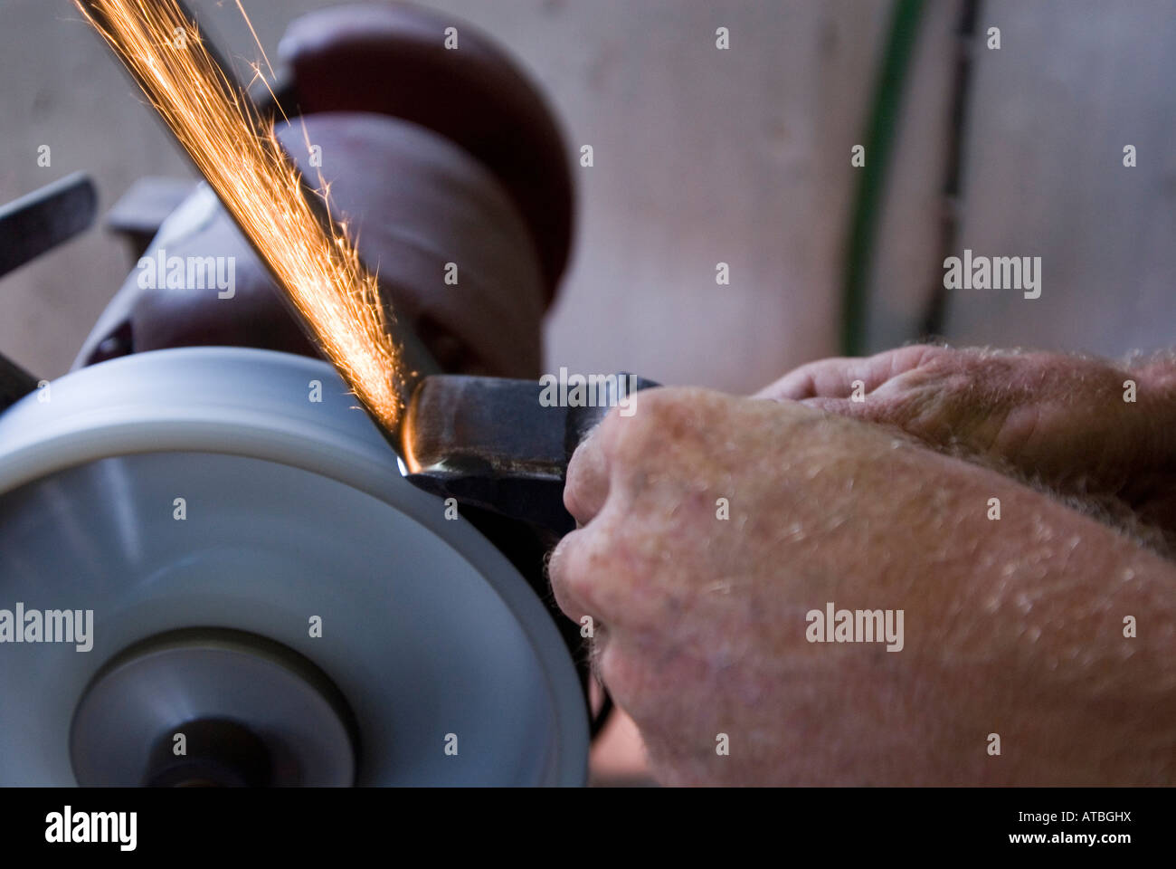 Alten Stil handgefertigte Eisen Arbeiter in einem kleinen shop, Schleifen und gestalten von Eisen auf einem Schleifstein Stockfoto