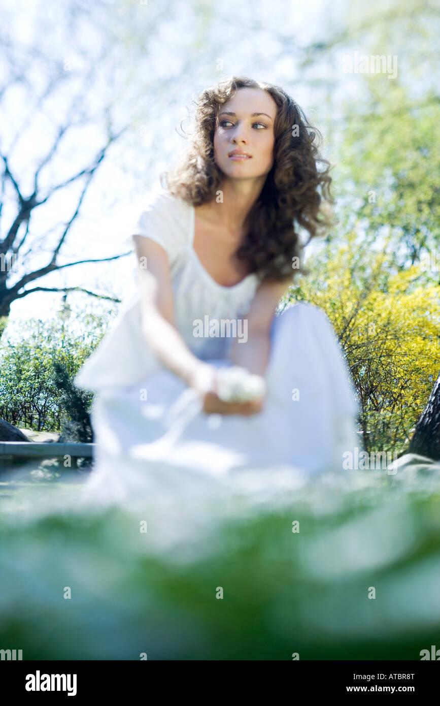 Junge Frau im Freien, hockend betrachtet von Oberflächenniveau wegsehen, Stockfoto