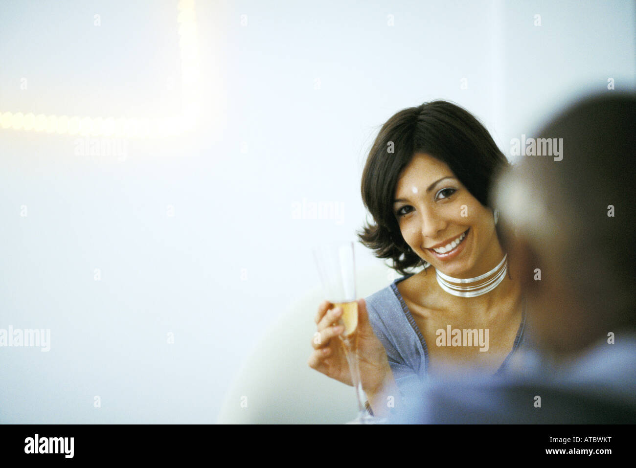 Frau hält Champagner Glas, lächelnd in die Kamera, Mann im Vordergrund Stockfoto
