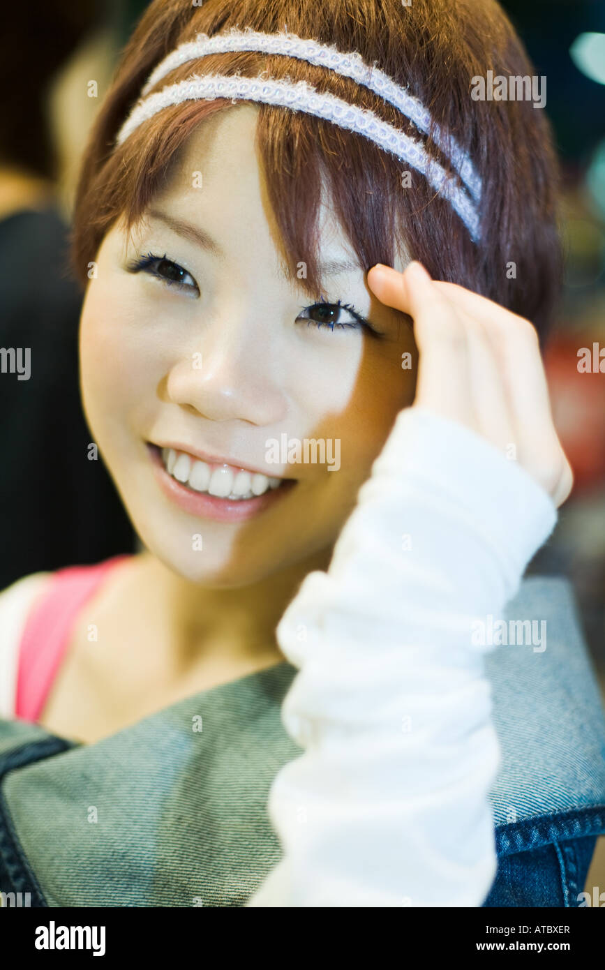 Junge Frau lächelnd, berühren Kopf, Nahaufnahme Stockfoto