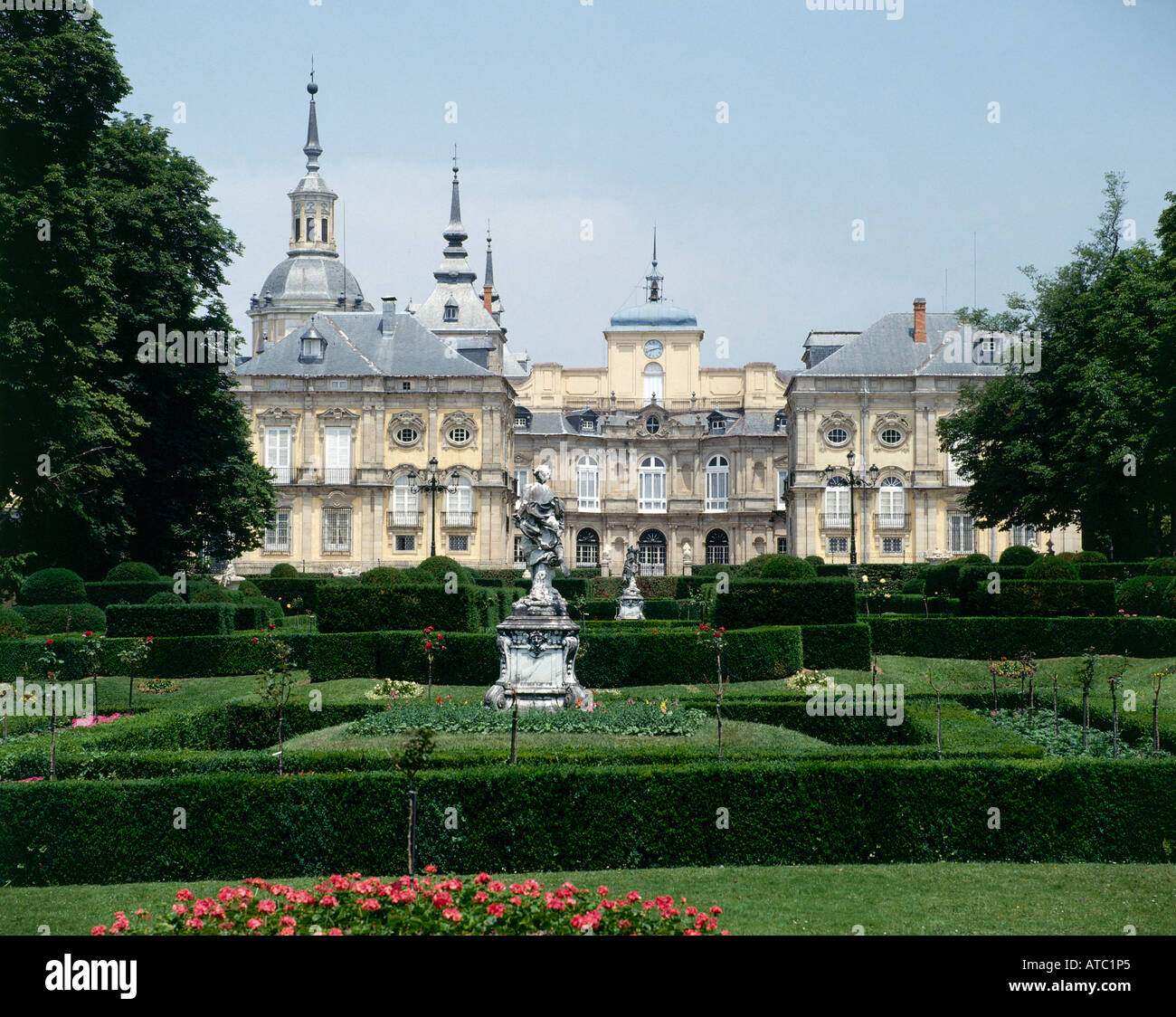 Formale Statuen inmitten von gepflegten Blumenbeeten und niedrige Hecken auf dem bewaldeten Gelände rund um die feine Gebäude von La Granja Stockfoto