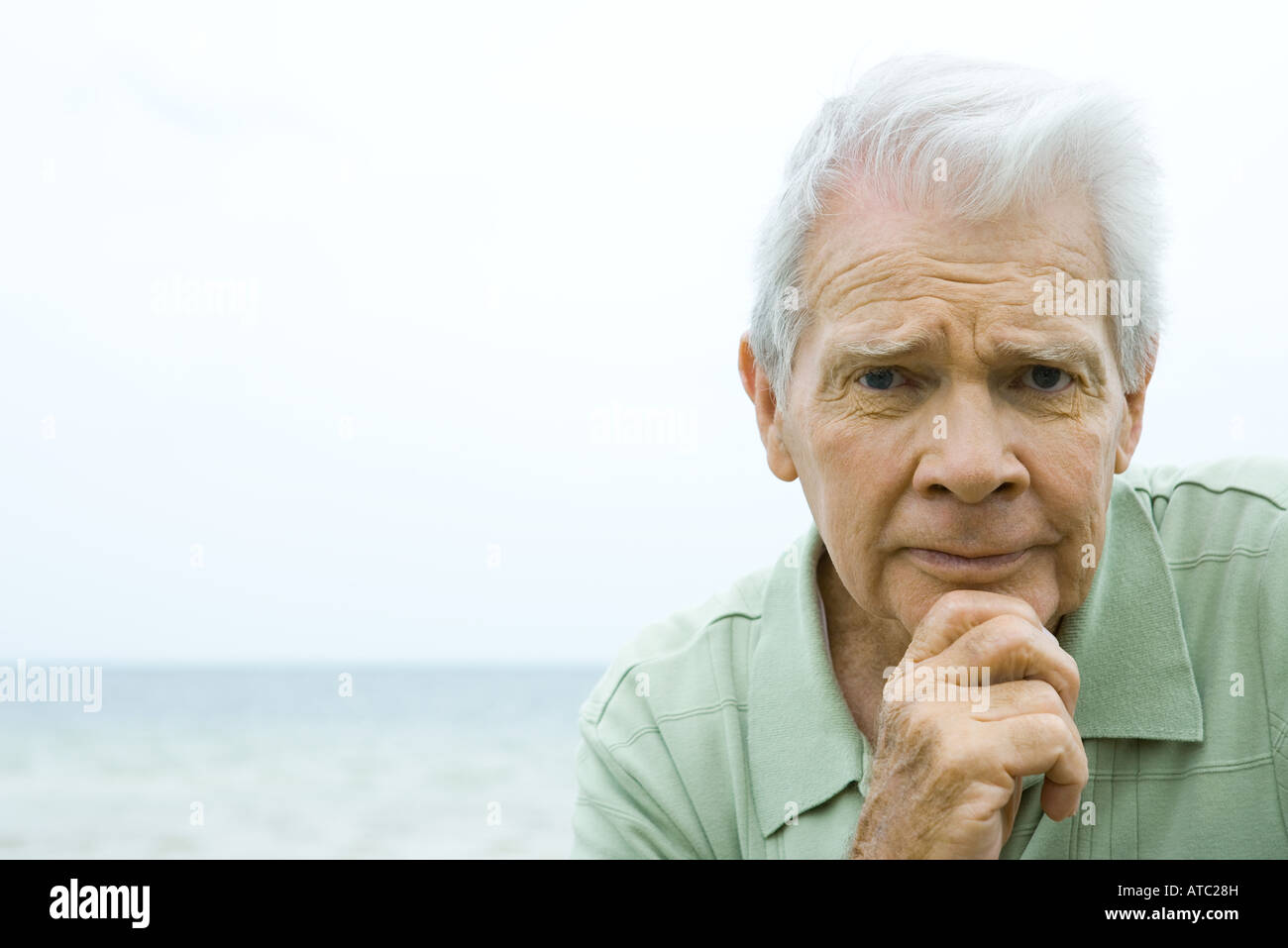 Senior woman gerunzelter Stirn, Hand unter Kinn, Blick in die Kamera Stockfoto