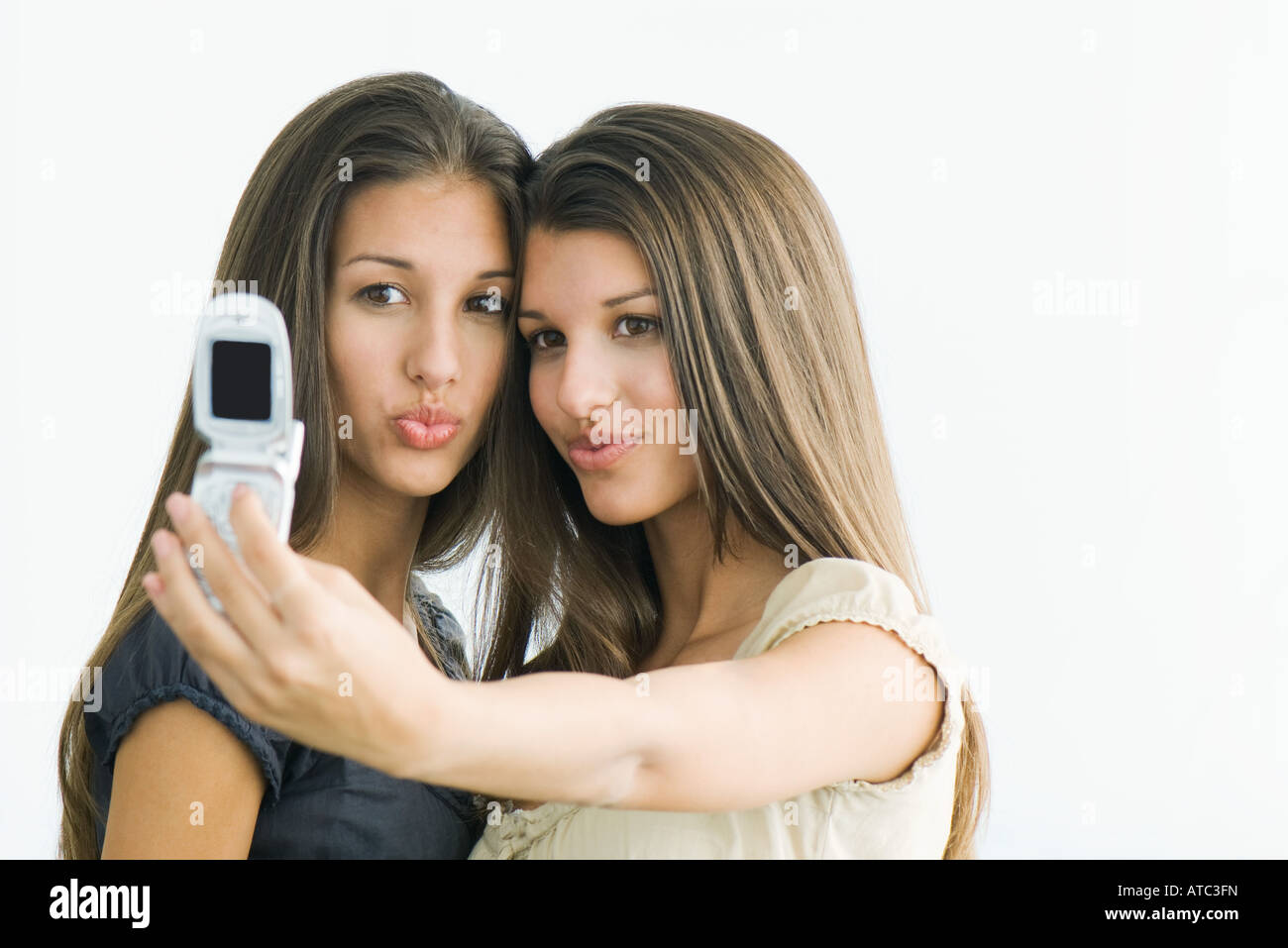 Teenager-Mädchen fotografieren selbst und Zwillingsschwester mit Handy Stockfoto