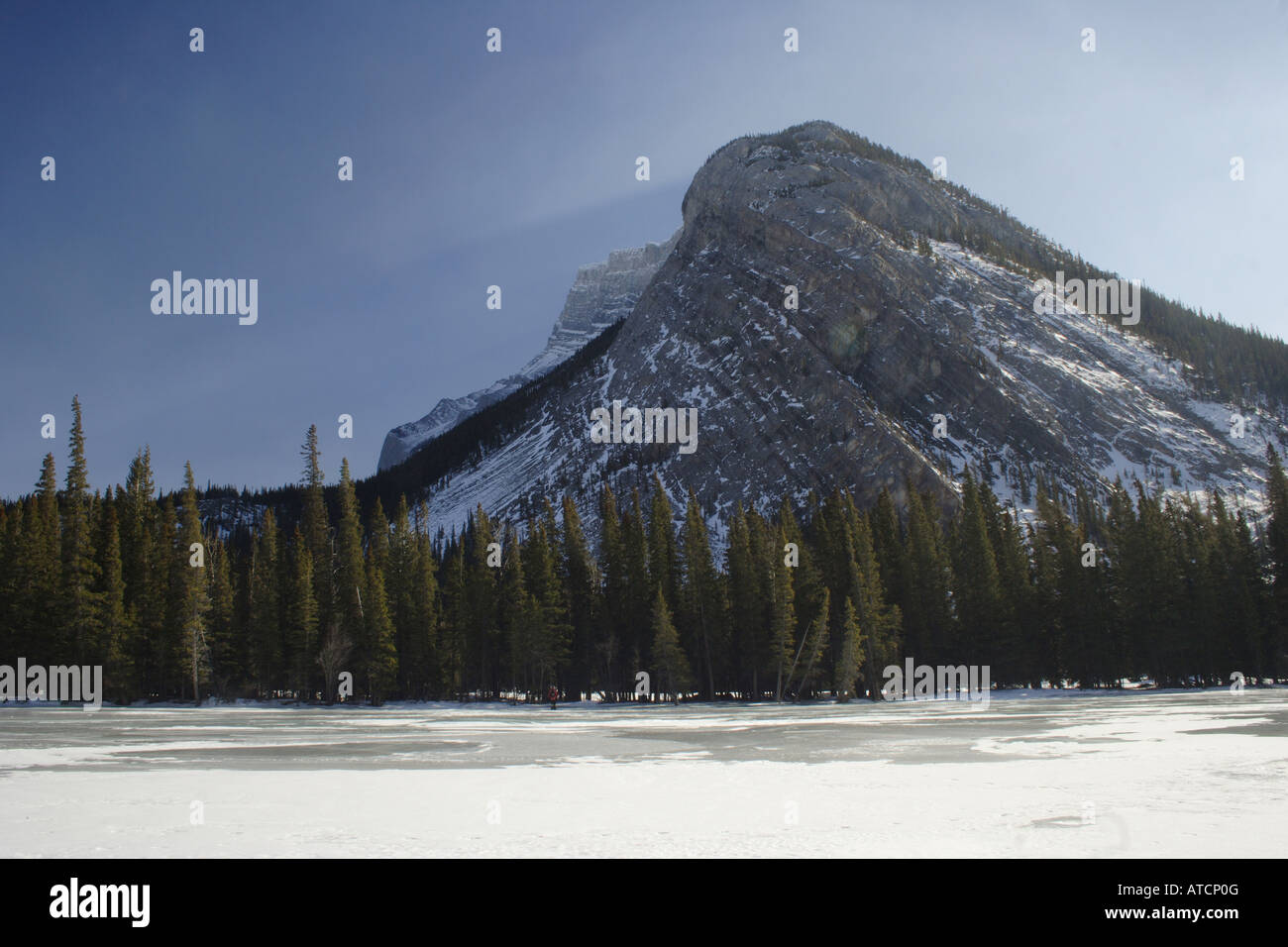 Schattenhafte Rockies über gefrorene Bow River im Banff Village, Alberta Stockfoto