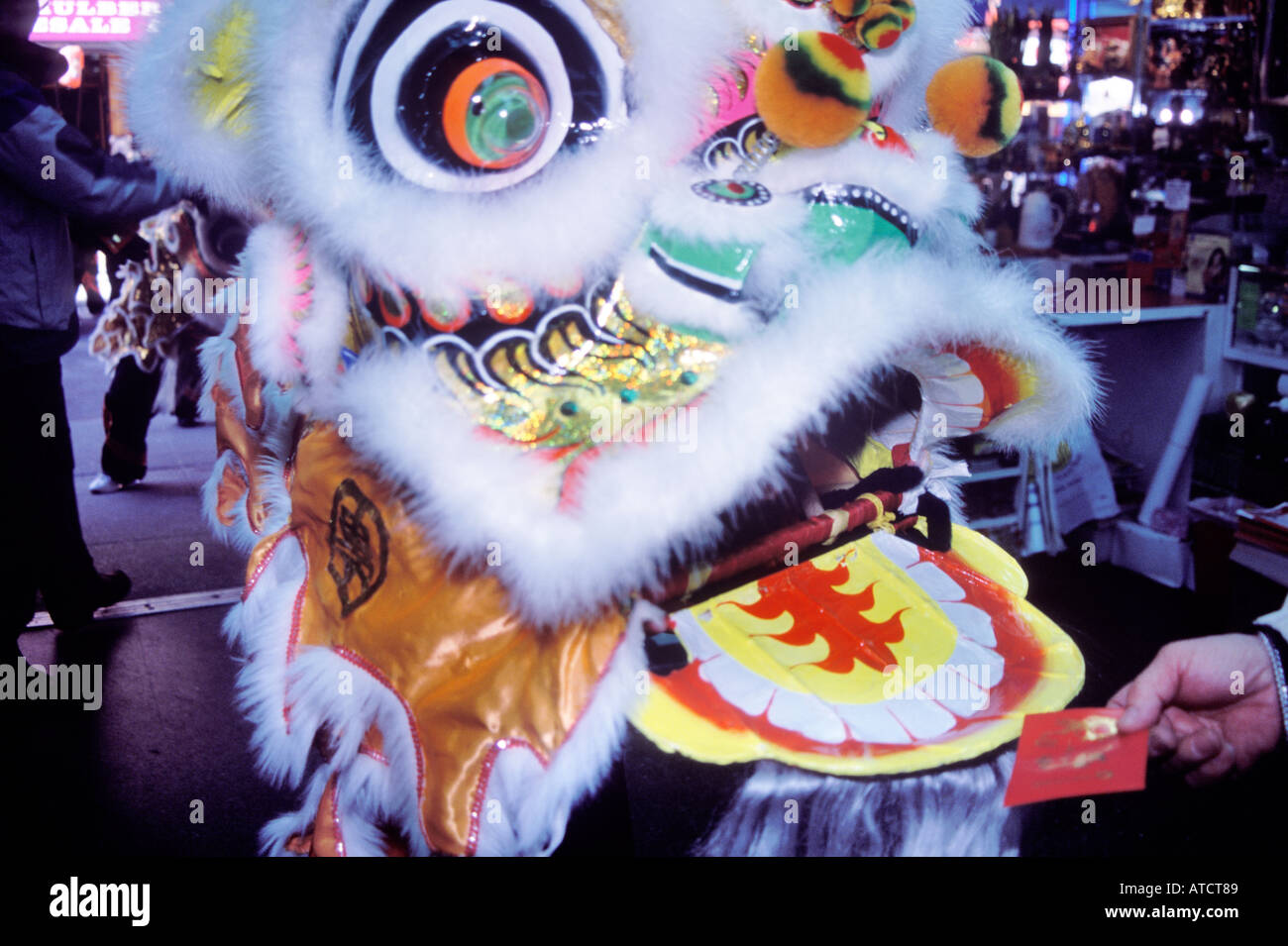 Ein Löwe tritt eine Einrichtung um einen roten Umschlag mit Geld von der Shop-Betreiber, jährliche Löwe Tänze, Chinatown, NYC gefüttert werden Stockfoto