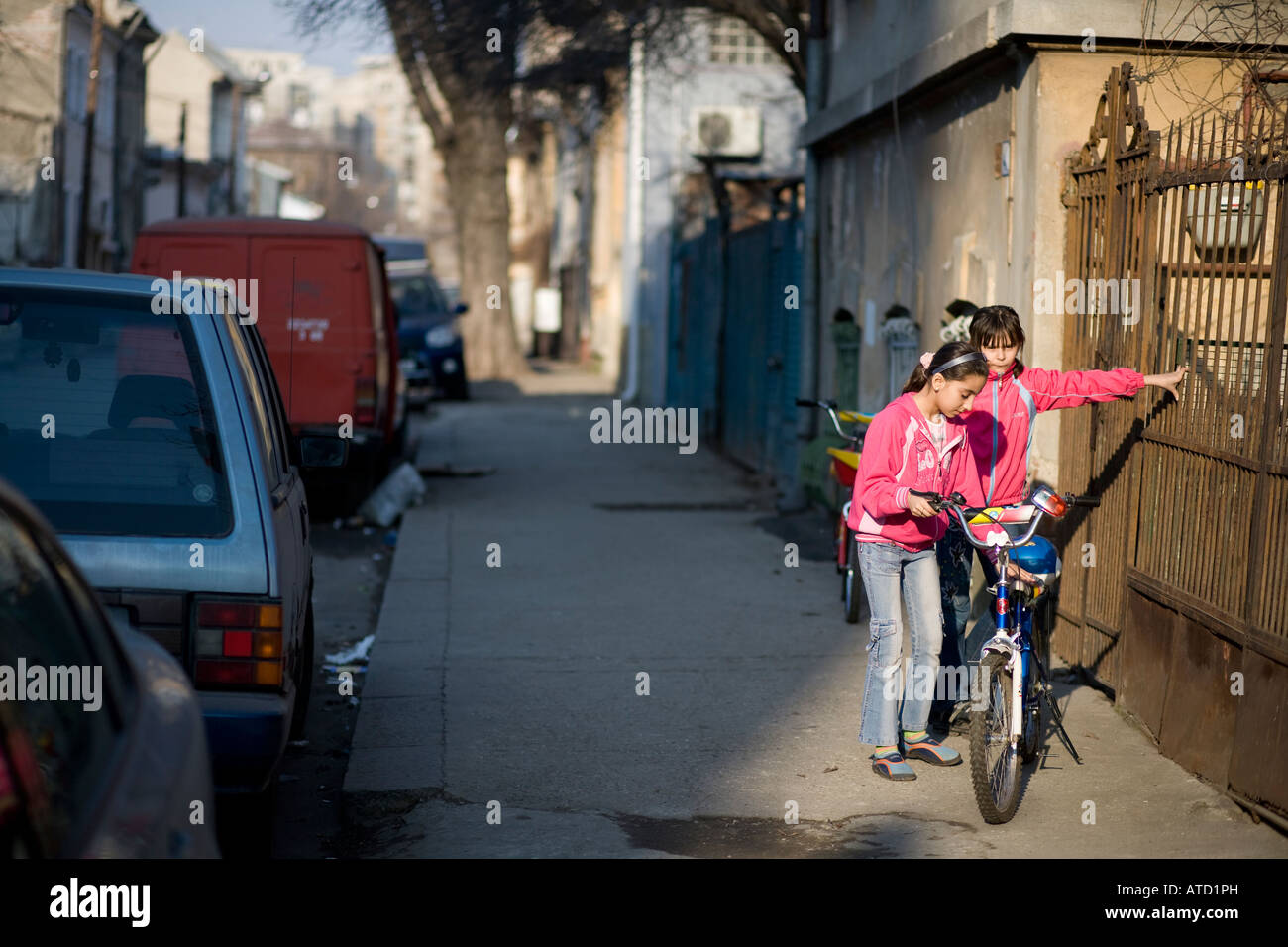Kinder auf einer Straße mit alten Häusern vor einem Zaun abstellen von Fahrrädern stehen im Sonnenlicht Stockfoto