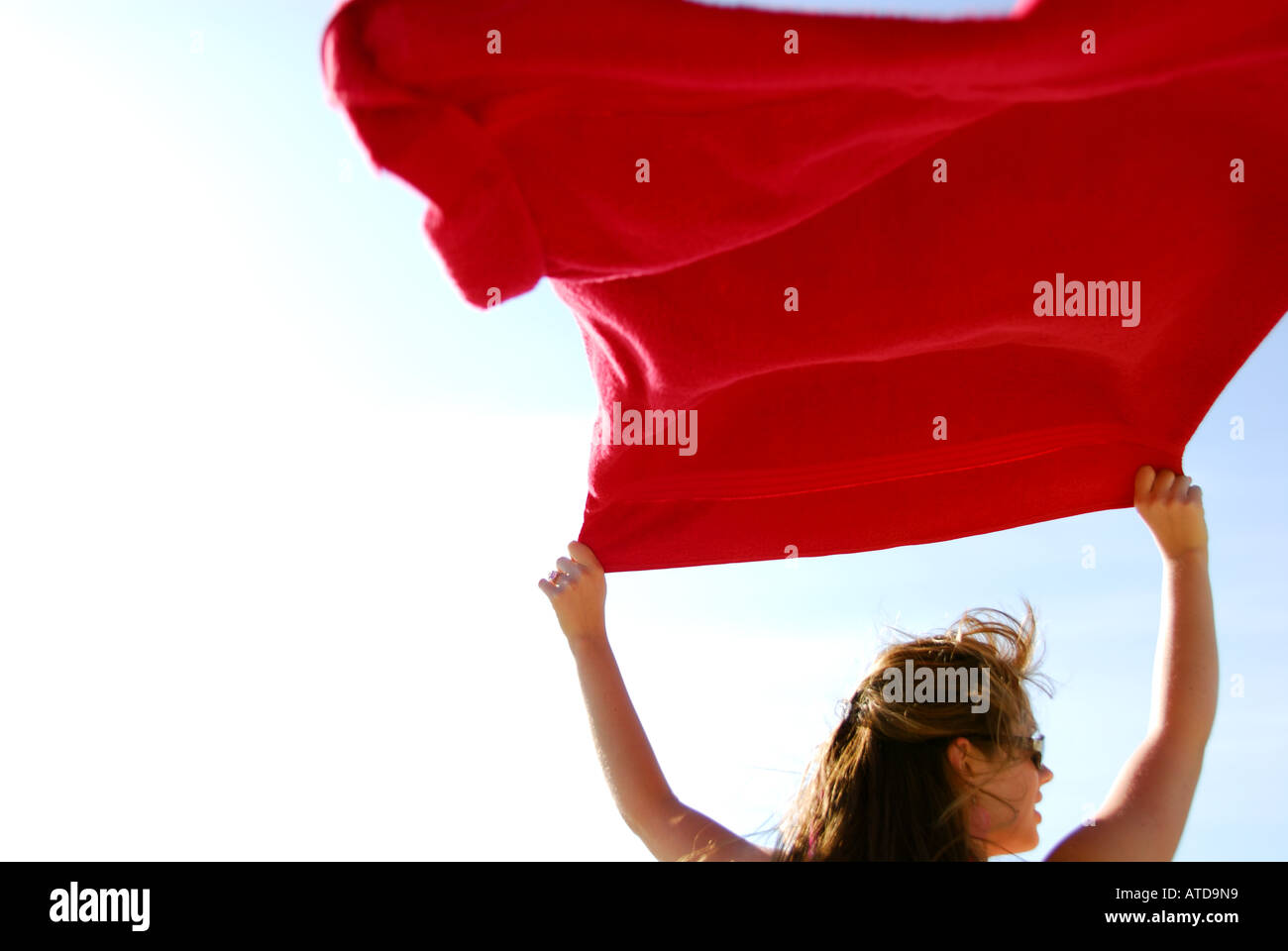 junge Frau mit roten Tuch im Wind am Strand Stockfoto