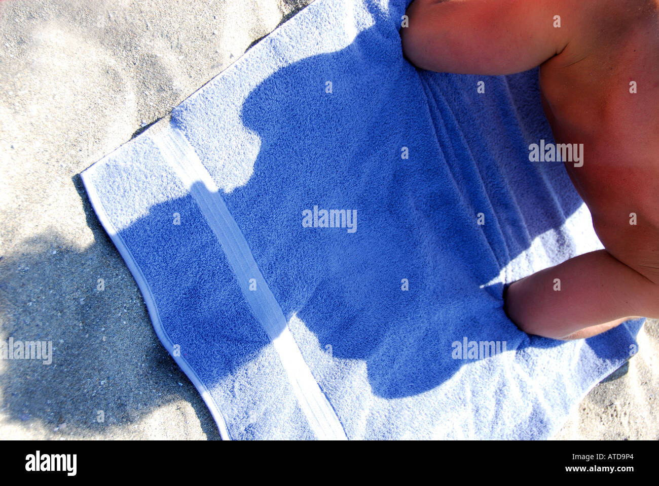 junger Mann stützte sich auf Handtuch am Strand Stockfoto