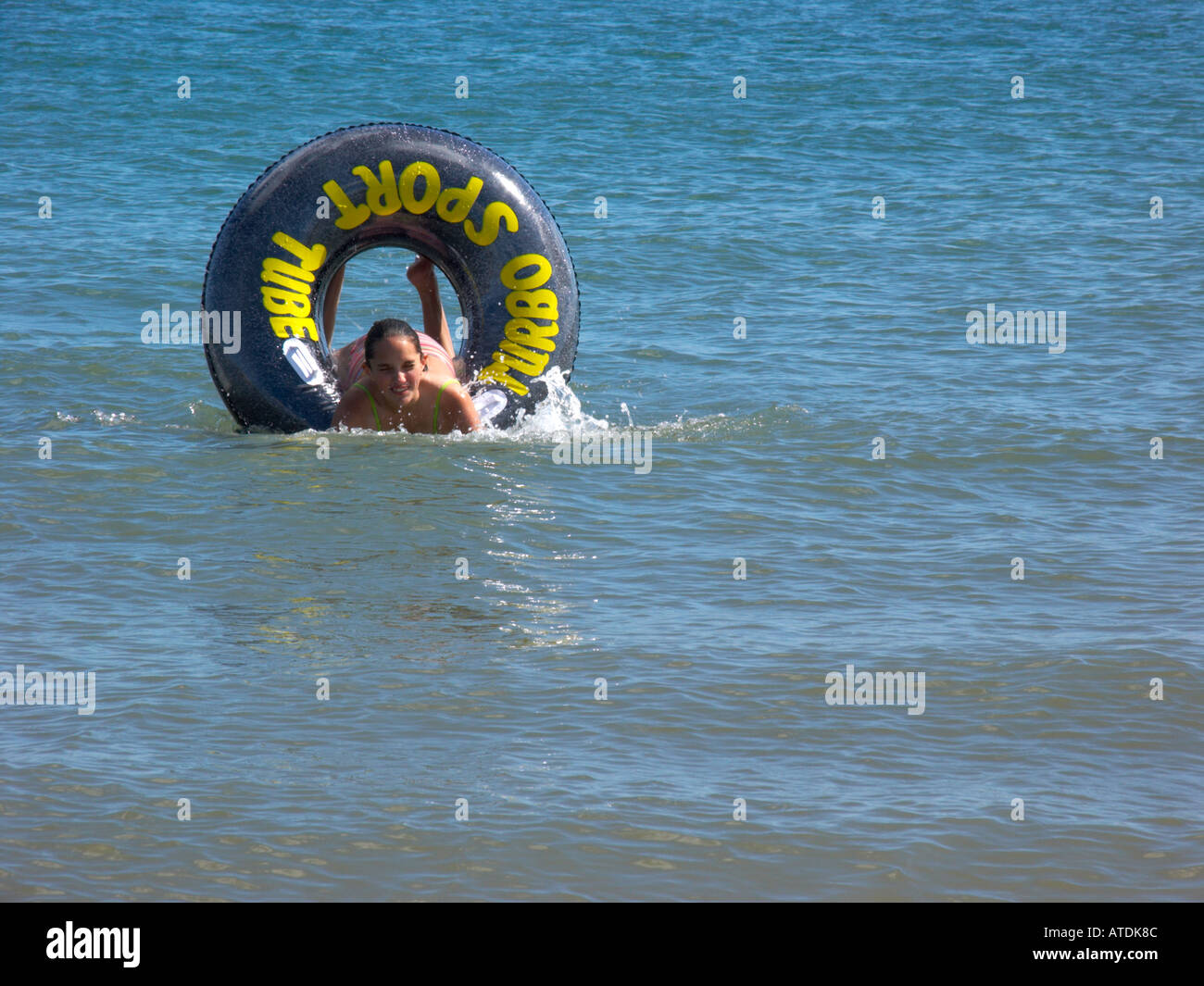 Tenby junge Mädchen spielen im Meer mit ring Stockfoto