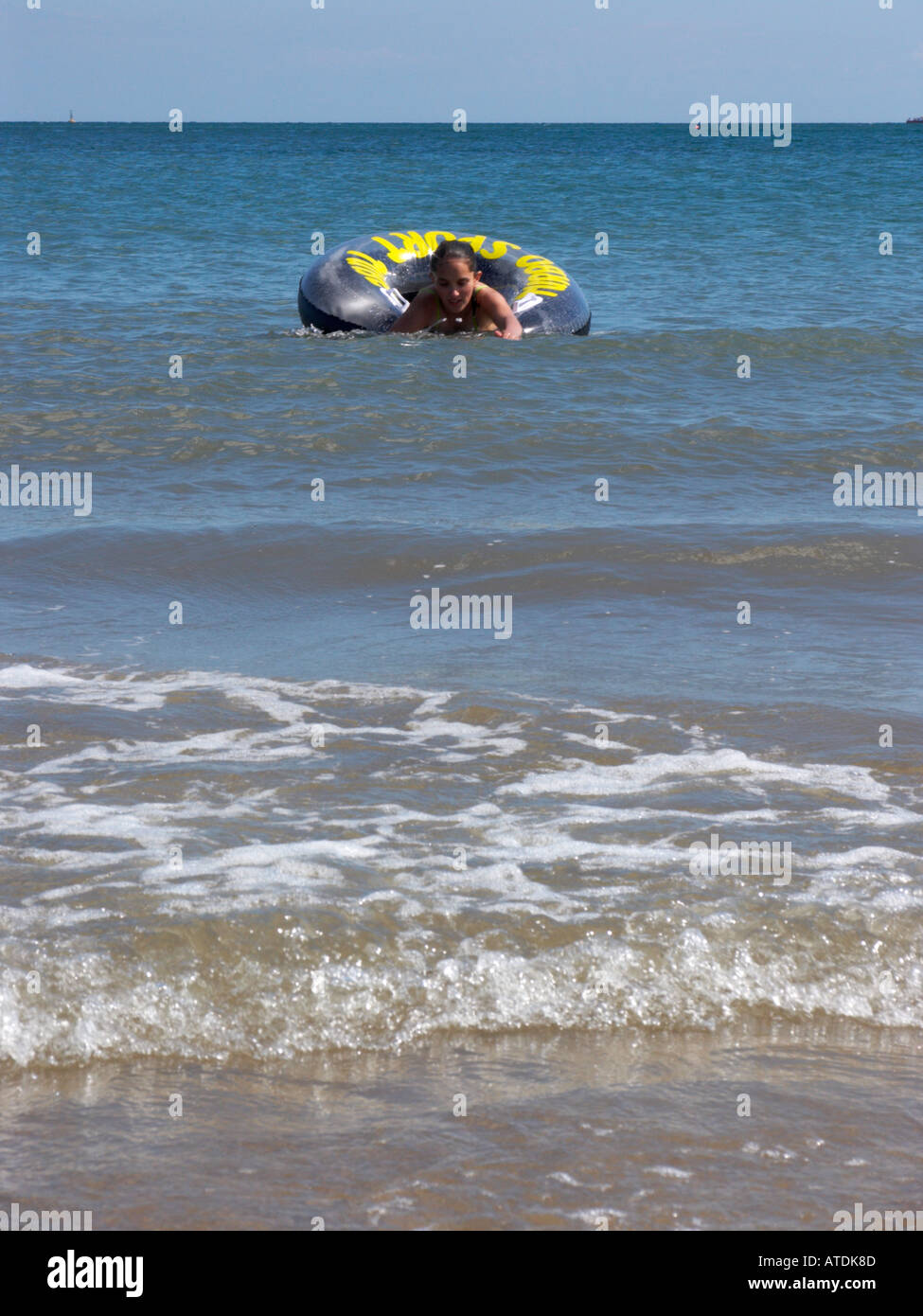 Tenby junge Mädchen spielen im Meer mit ring Stockfoto