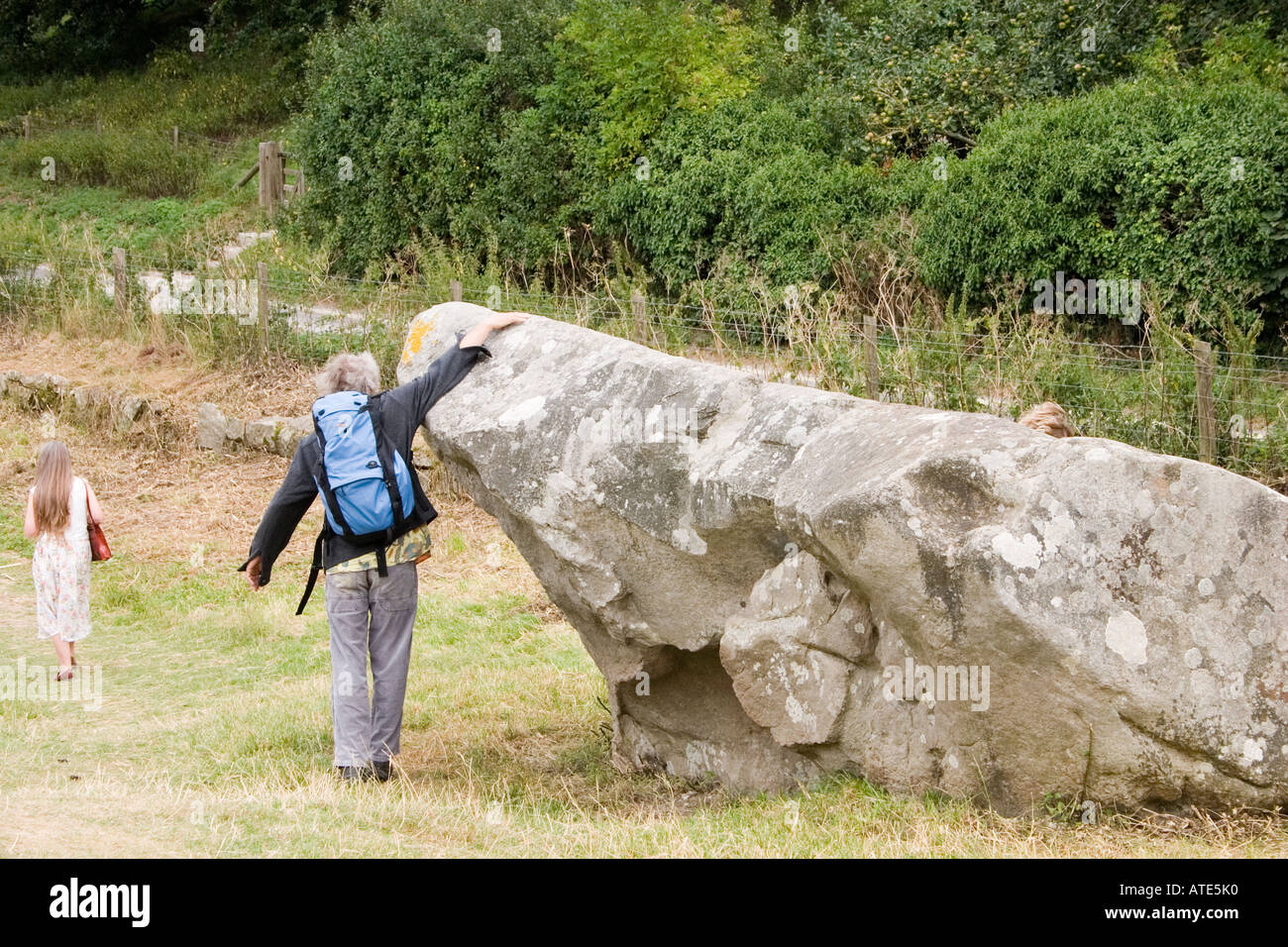 Besucher, die Zwiesprache mit einem riesigen gefallenen Stein Avebury circle Wiltshire UK Stockfoto