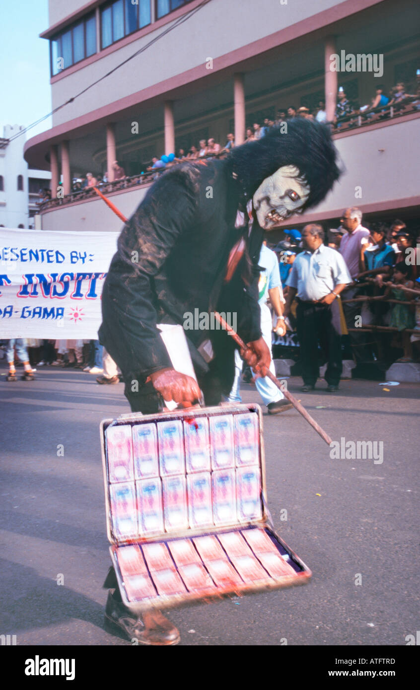 Goa Karneval Teilnehmer maskiert als Zombie Geschäftsmann mit Aktenkoffer mit indischen Geld Währung eingereicht. Rupien. Stockfoto