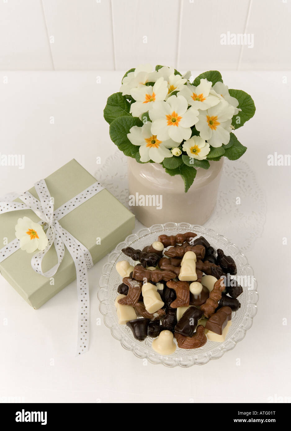 Primeln in einem Vintage China Topf, Geschenkbox mit Bändern und Schleifen und eine Auswahl von Miniatur-Oster-Bunny-Pralinen Stockfoto