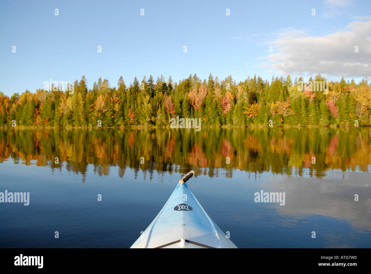 Stock Bild von einem blauen Kajak in Richtung eines Hügels bedeckt in schillernden Herbstfarben auf Kelly Creek Lake in New Brunswick, Kanada Stockfoto