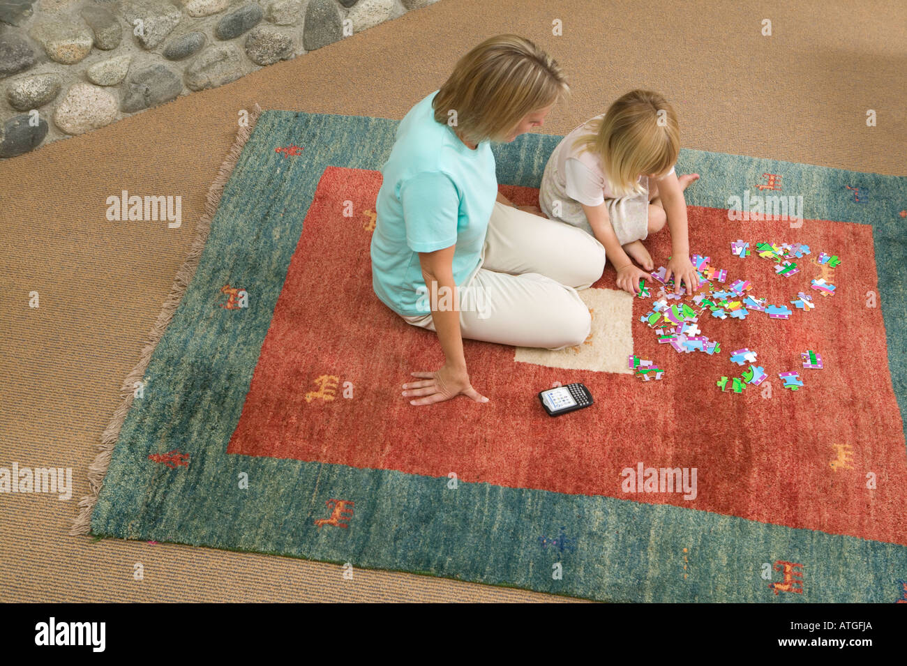 Mama hilft mit einem Jigsaw Puzzle-Blackberry-Gerät in der Nähe Stockfoto