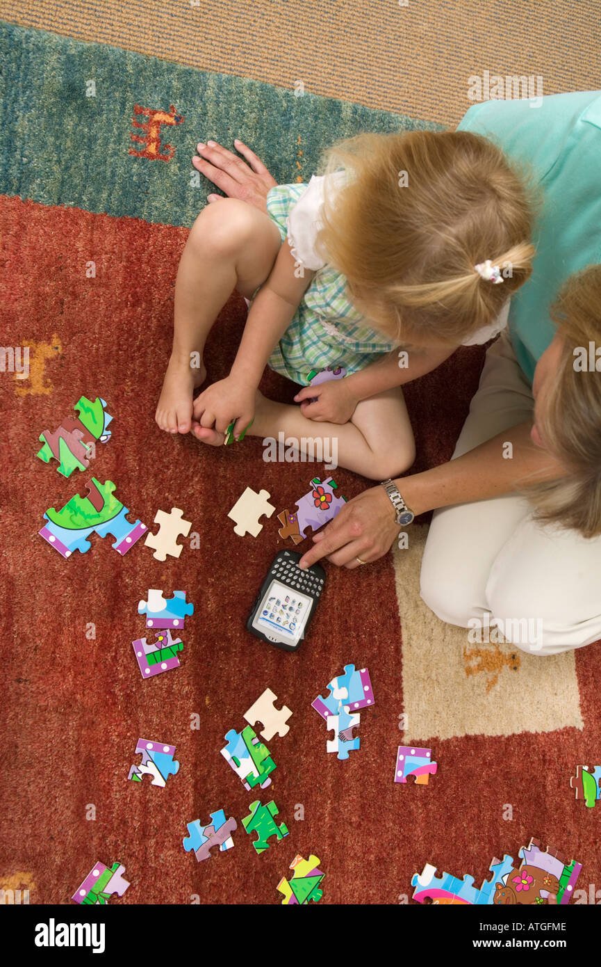 Mama hilft mit einem Jigsaw Puzzle-Blackberry-Gerät in der Nähe Stockfoto