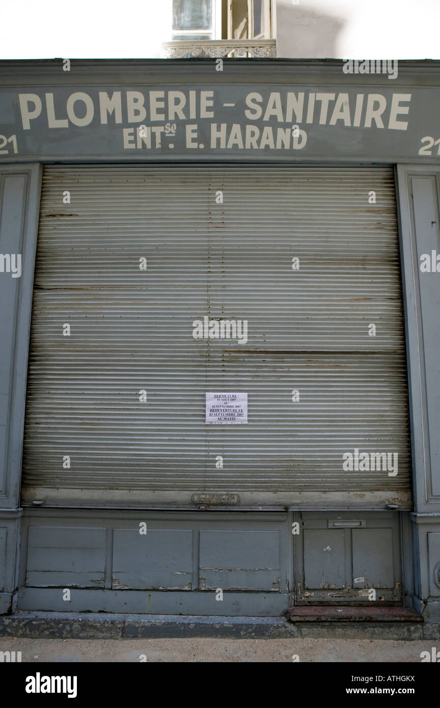 Geschlossene Metallvorhang vor einem alten Sanitär-Shop in Paris geschlossen für den Sommer Stockfoto