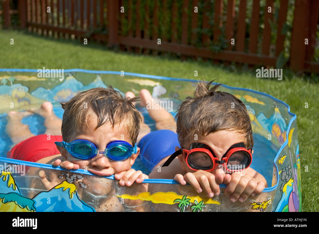 zwei kleine Jungs in einem Planschbecken im Garten liegend Stockfoto