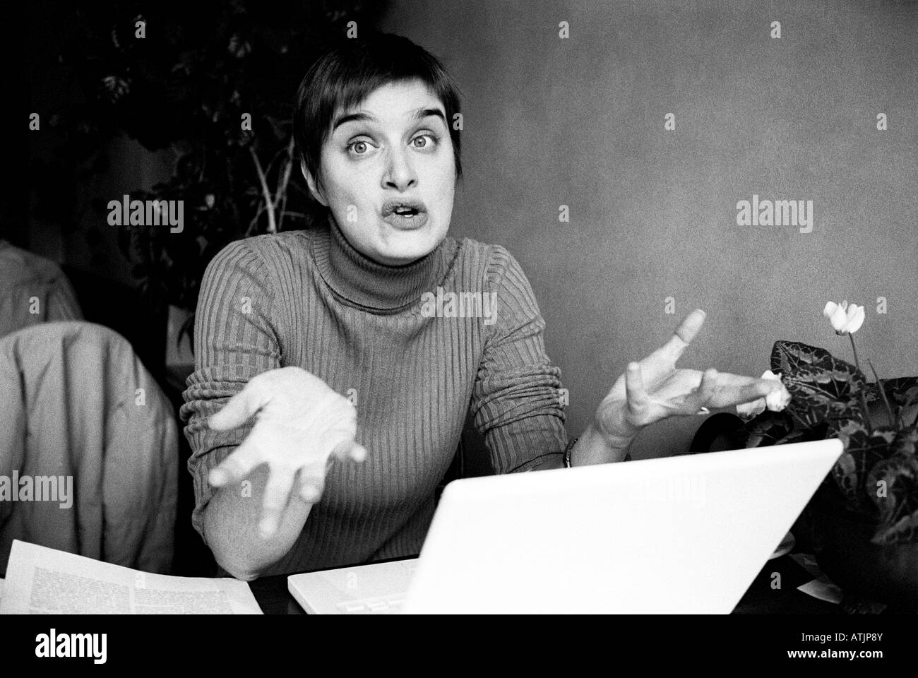 Kurzhaarige junge Frau mit Laptop-Computer sitzend streckt ihre Hände mit einem Ausdruck des Unglaubens. Stockfoto