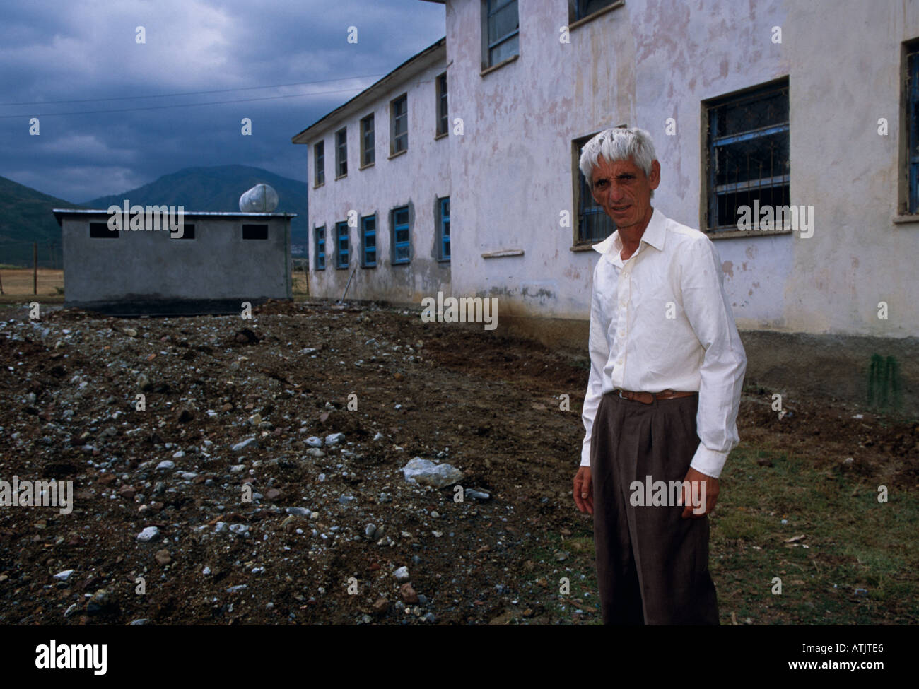 Grauhaariger Mann auf Ödland von baufälligen Gebäude mit Bergen im Hintergrund, Porträt, Kukes, Albanien, Südosteuropa Stockfoto