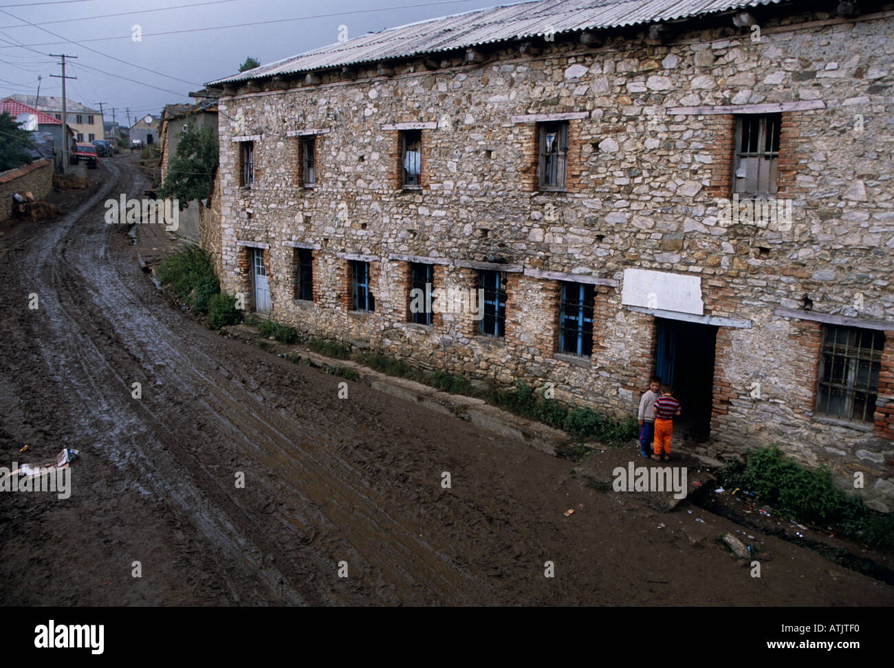 Landwirtschaftliche Gebäude durch schlammigen Feldweg in Dorf, Provinz von Kukes in Albanien, Südosteuropa Stockfoto