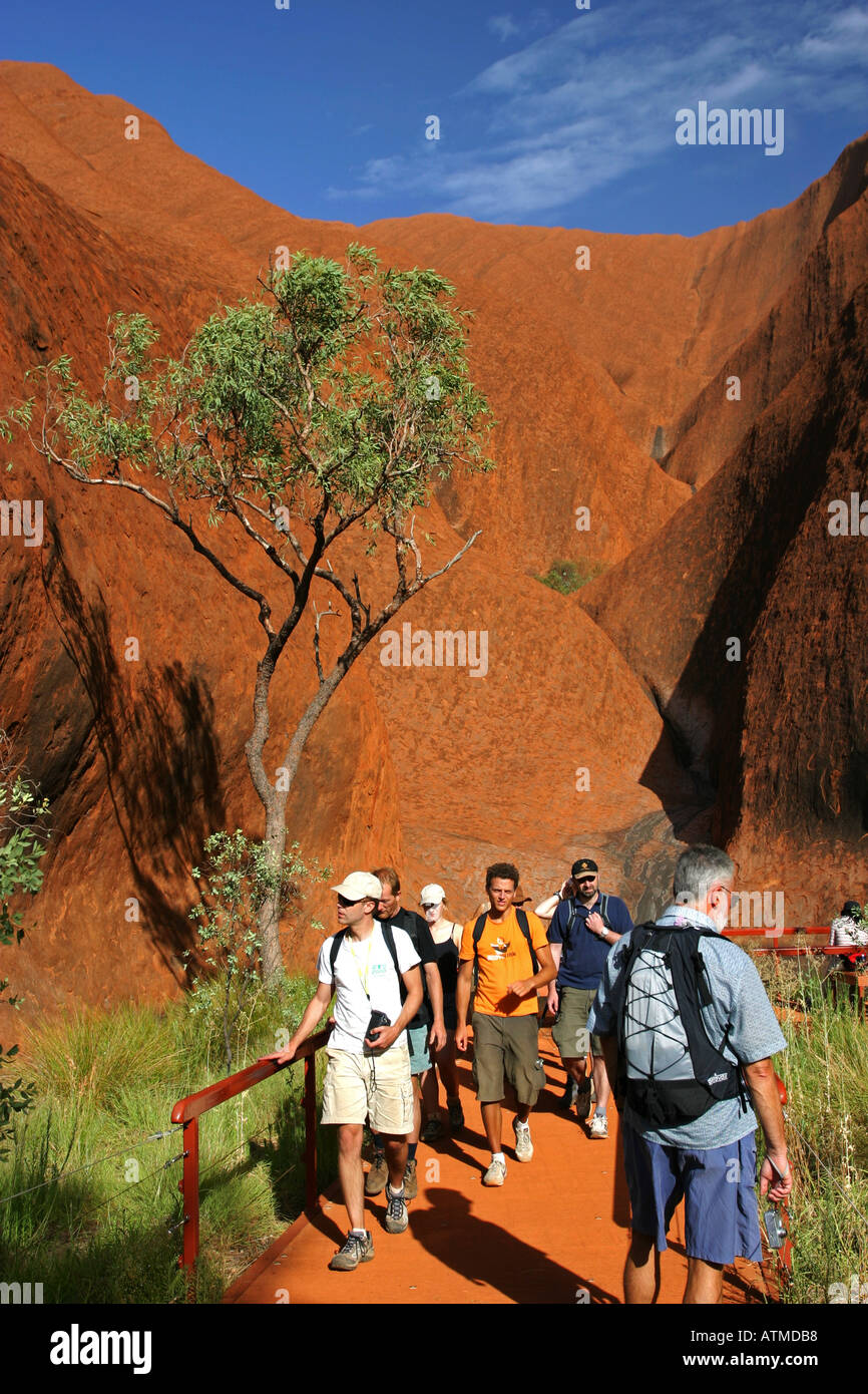 Massen von Touristen zu Fuß um die Basis der berühmten Ayers rock Uluru auf der Kreisbahn Northern Territory Australien Stockfoto