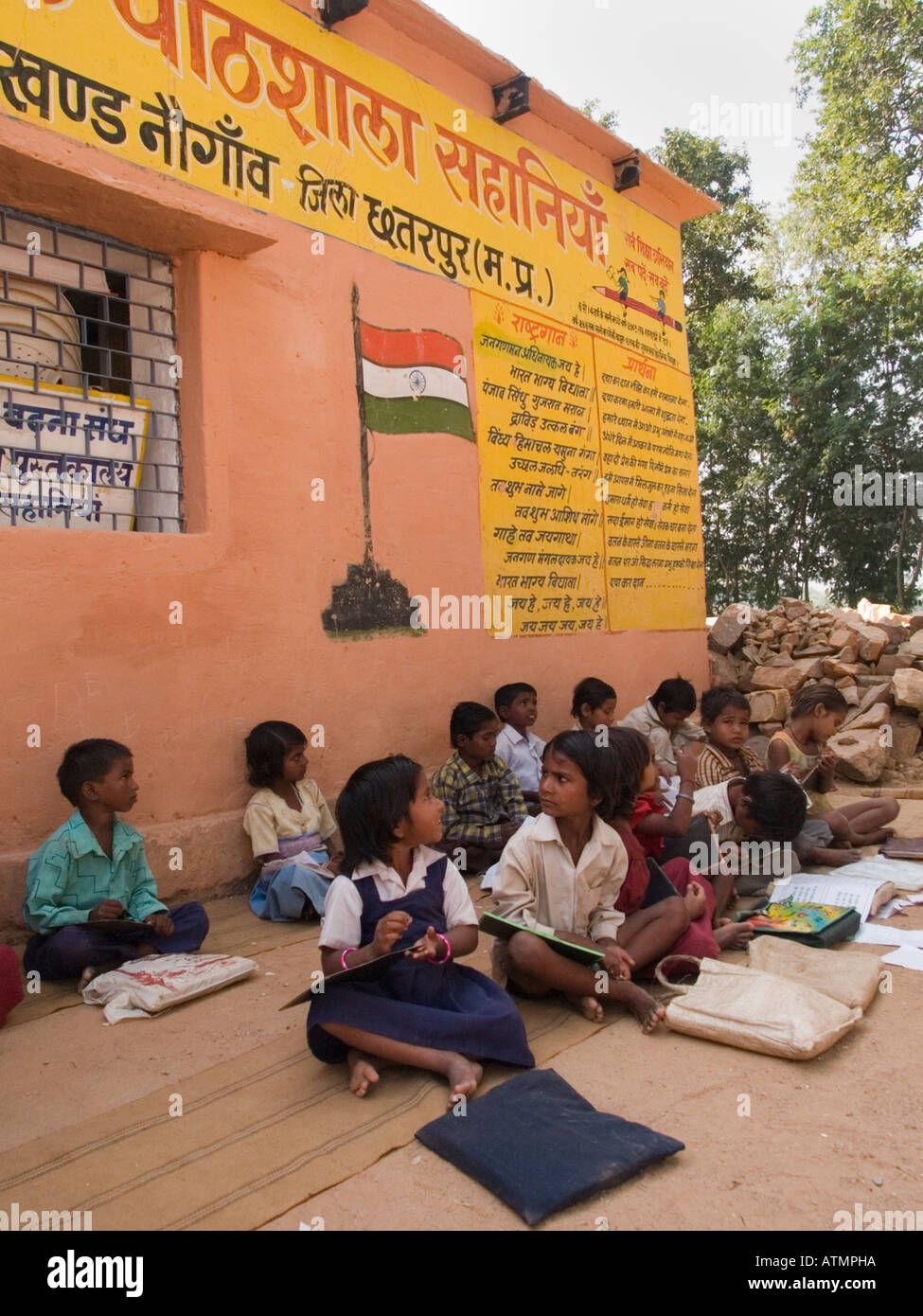Reihen von junior School Kinder sitzen am Boden im Schatten außerhalb der ländlichen Dorfschule für ein Outdoor-Lektion. Pradesh, Indien Stockfoto
