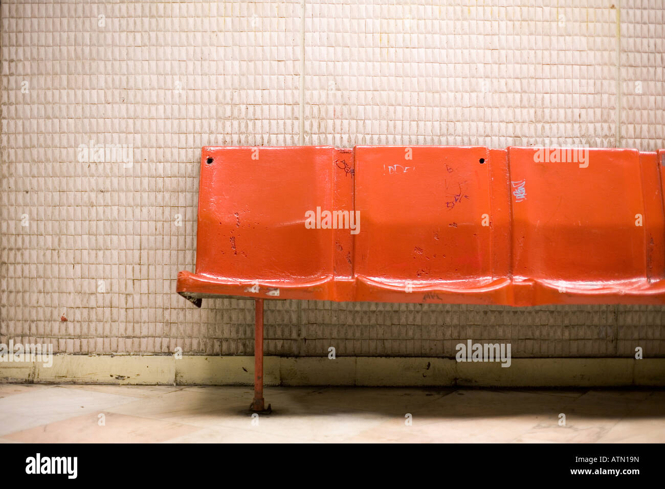 leere hell orange Kunststoff-Bank in einer u-Bahnstation mit einem schlechten Zustand Stockfoto